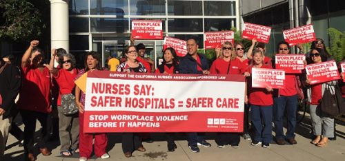 an image of a large group of nurses picketing and protesting with large red signs and bright red shirts
